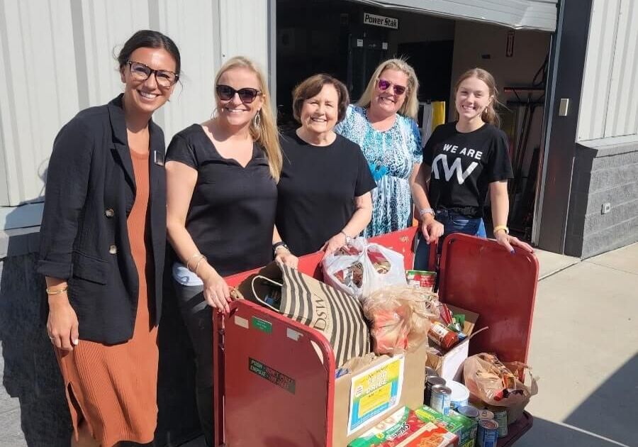 Our members standing next to a cart full of donated food items for the 2022 June Harvest