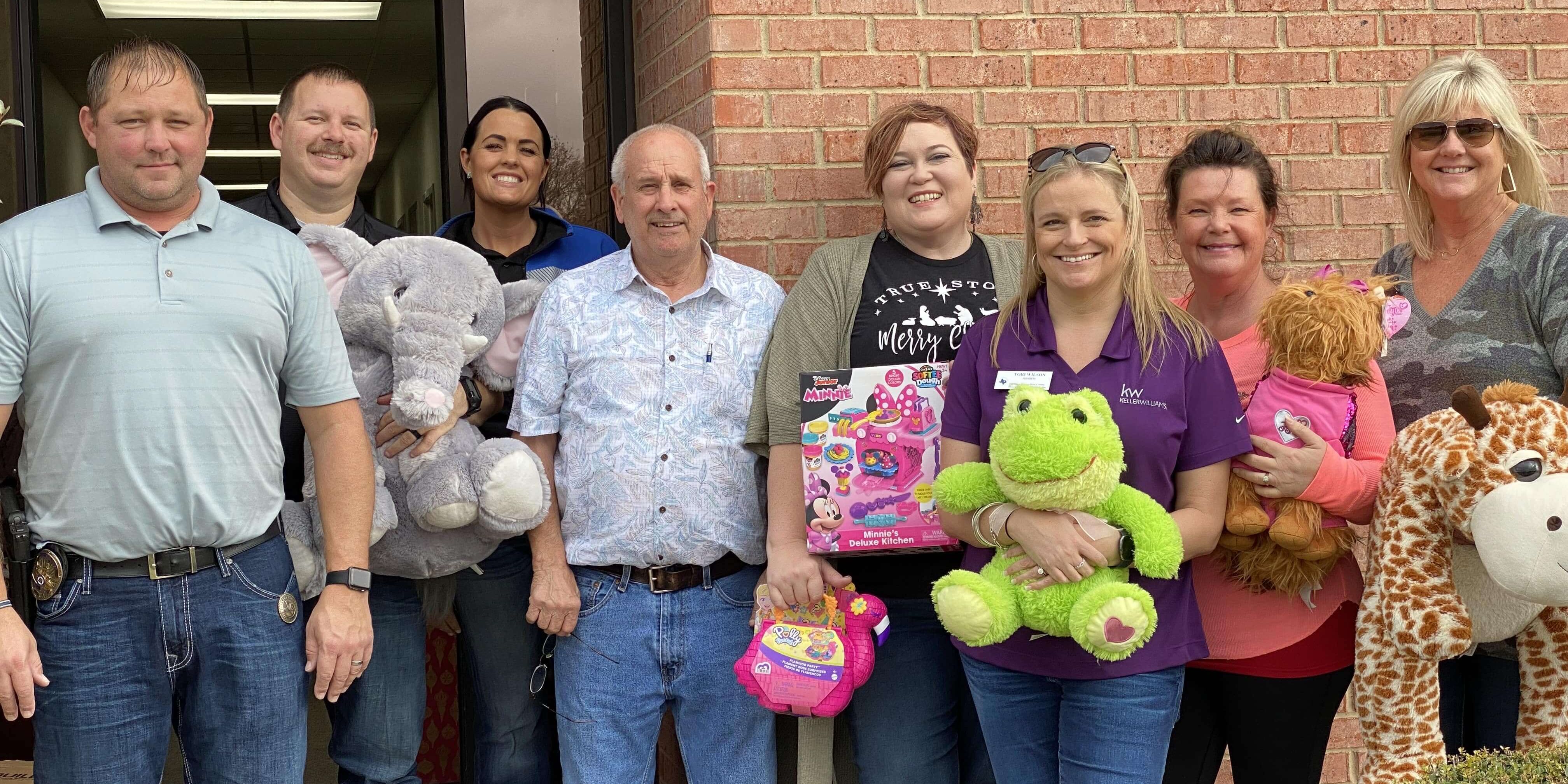 Our members standing side-by-side holding donated toys for children.