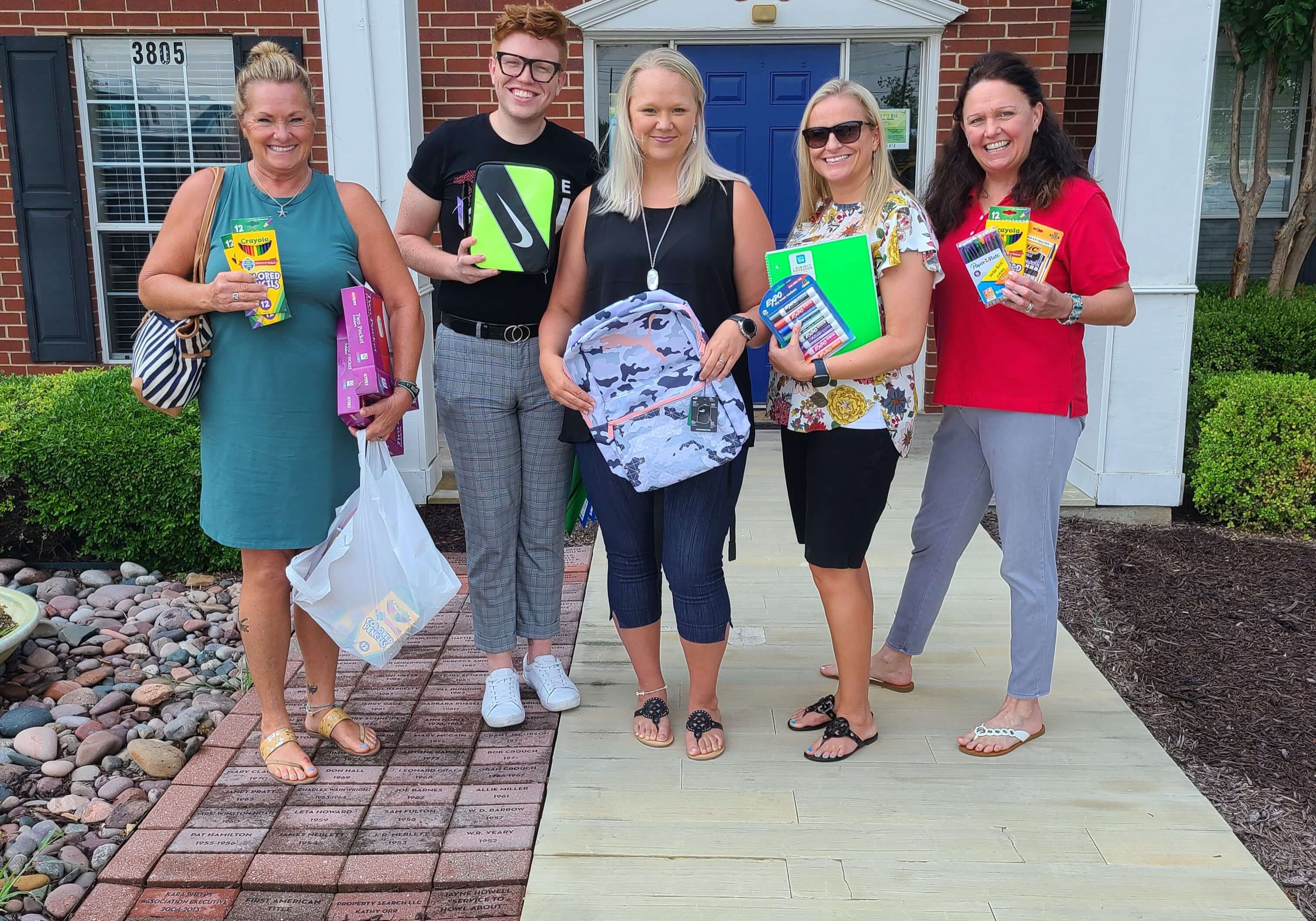 Some of our members in front of our office holding school supplies.